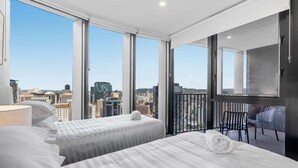 A hotel room with two beds, a balcony with a chair, and a city view. - Luxury Sky-high CBD Apt | Pool, Gym, Parking (Brisbane City)