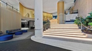 A modern interior with a staircase, seating areas, and a plant. - Luxury Sky-high CBD Apt | Pool, Gym, Parking (Brisbane City)