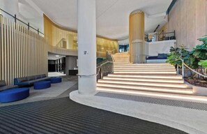 Ein modernes Interieur mit Treppe, Sitzbereichen und einer Pflanze.