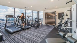 A gym with treadmills, exercise bikes, and weight machines. - Luxury Sky-high CBD Apt | Pool, Gym, Parking (Brisbane City)