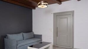 A room with a grey sofa, a white coffee table, a grey door, and a ceiling light fixture.