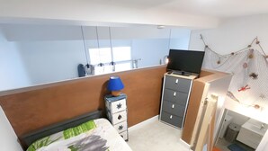 A bedroom with a bed, a dresser, a TV on a stand, and a window. - The Geraniums Apartment - ref 305 (La Tranche-sur-Mer)