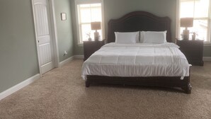 Una camera da letto con un letto grande, due comodini, una porta e una finestra con persiane.