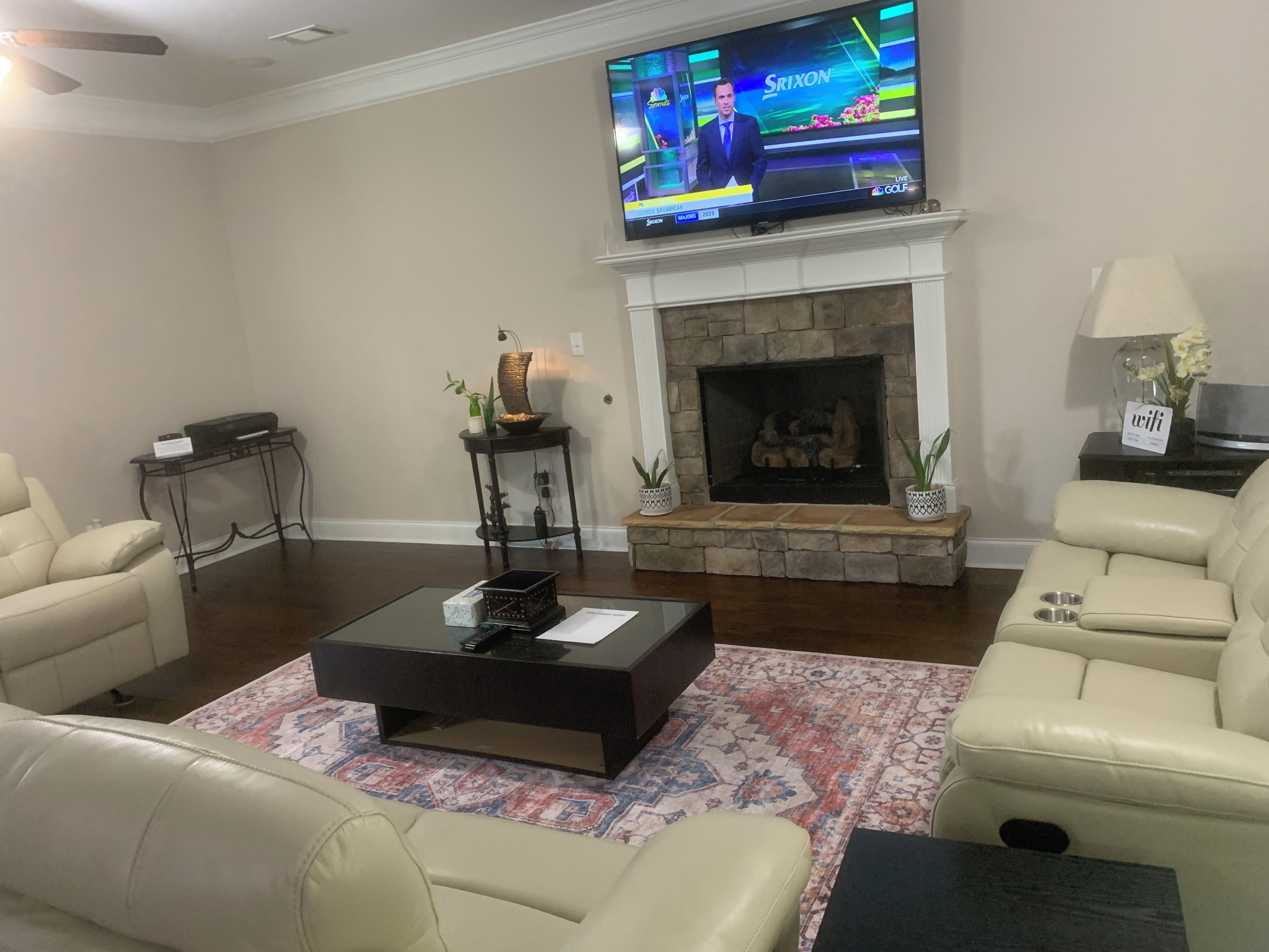Uma sala de estar com televisão, lareira, sofás de couro e uma mesa de centro.