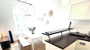 A modern kitchen with a dining area, a trash bin, and a pendant light. - Central Apartment for up to 10 Guests (Hamburg)