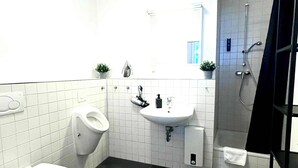 A bathroom with a toilet, urinal, sink, and shower. - Central Apartment for up to 10 Guests (Hamburg)