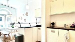 A modern kitchen with white cabinets, a wooden floor, and a dining area with a table and chairs. - Central Apartment for up to 10 Guests (Hamburg)