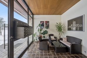 Un patio moderno con mobiliario de mimbre, un vidrio y un cuadro de paisaje urbano.
