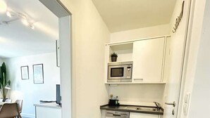 Una cucina compatta con mobili bianchi, un forno a microonde e una lavastoviglie.