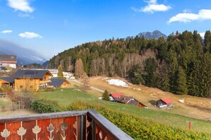 Paisagem montanhosa com uma cabana de madeira e um edifício com telhado vermelho.