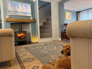 A cozy living room with a fireplace, a dog, and a staircase. - York Cottage (Reydon)