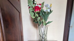 Une table en bois, un vase de fleurs, un panier en osier et une porte.
