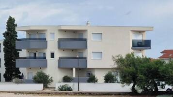 A multi-story building with balconies, a flat roof, and a white facade.