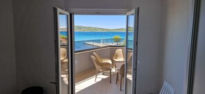 A balcony with a view of a body of water, a table, and two chairs. - Mare Anima Apartments (Srima)