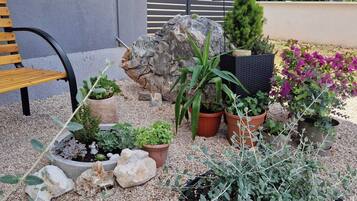 A garden with various potted plants, a bench, and a rock formation.