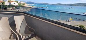 A balcony with a view of a beach and the sea, featuring a seating area with chairs and a table. - Mare Anima Apartments (Srima)