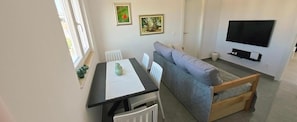 A compact living space with a sofa, a dining table, a TV, and artwork on the walls. - Mare Anima Apartments (Srima)