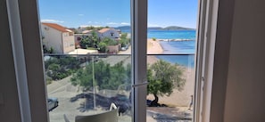 A balcony with a view of a coastal area, including a beach and boats. - Mare Anima Apartments (Srima)