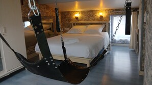 Une chambre à coucher avec un lit, un fauteuil suspendu et une table de chevet.