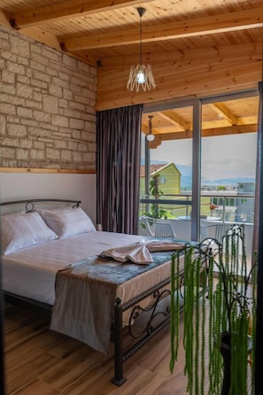 Un dormitorio con cama, una planta colgante y vista a un edificio por la ventana.