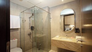A modern bathroom with a glass-enclosed shower, a marble sink, and a large mirror. - Louis Kienne Suite Cikarang (Cikarang)