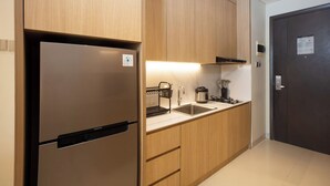 A modern kitchen with wooden cabinets, a stainless steel refrigerator, a sink, and a stove. - Louis Kienne Suite Cikarang (Cikarang)