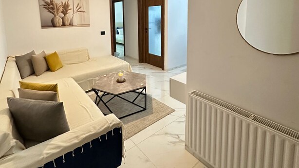 A modern living room with a sofa, coffee table, and a large mirror.