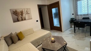 A modern living room with a sofa, a coffee table, and a dining area with a table and chairs.