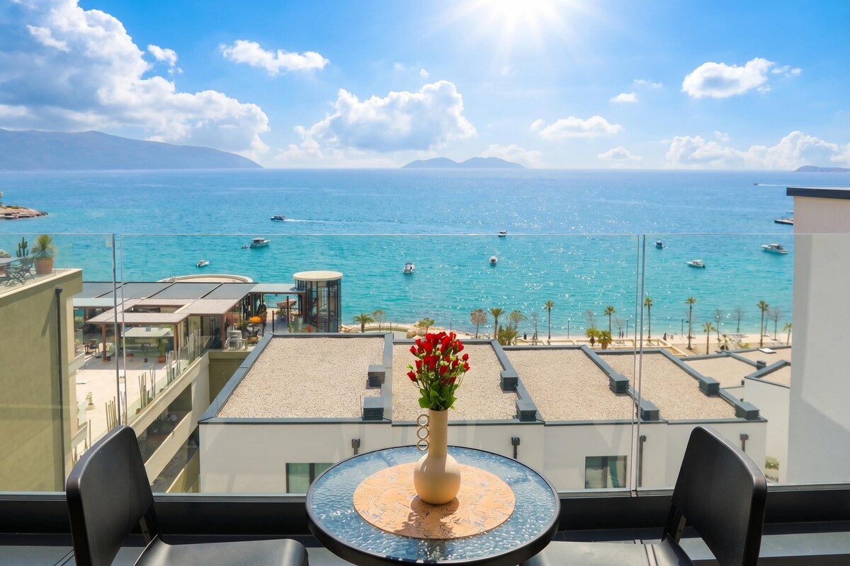 A balcony with a table, chairs, and a vase of flowers.
