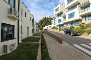A modern residential street with apartment buildings, a pedestrian crossing, and a parked car. - Velaris Apartments (Vlorë)