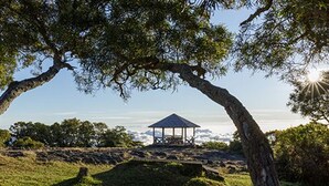 A gazebo on a grassy hill with a clear view of the ocean. - Charming Cottage with Sea View and Jacuzzi in Saint-Paul (Le Guillaume)