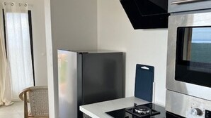 A modern kitchen with a built-in gas stove, a stainless steel refrigerator, and a microwave. - Charming Cottage with Sea View and Jacuzzi in Saint-Paul (Le Guillaume)