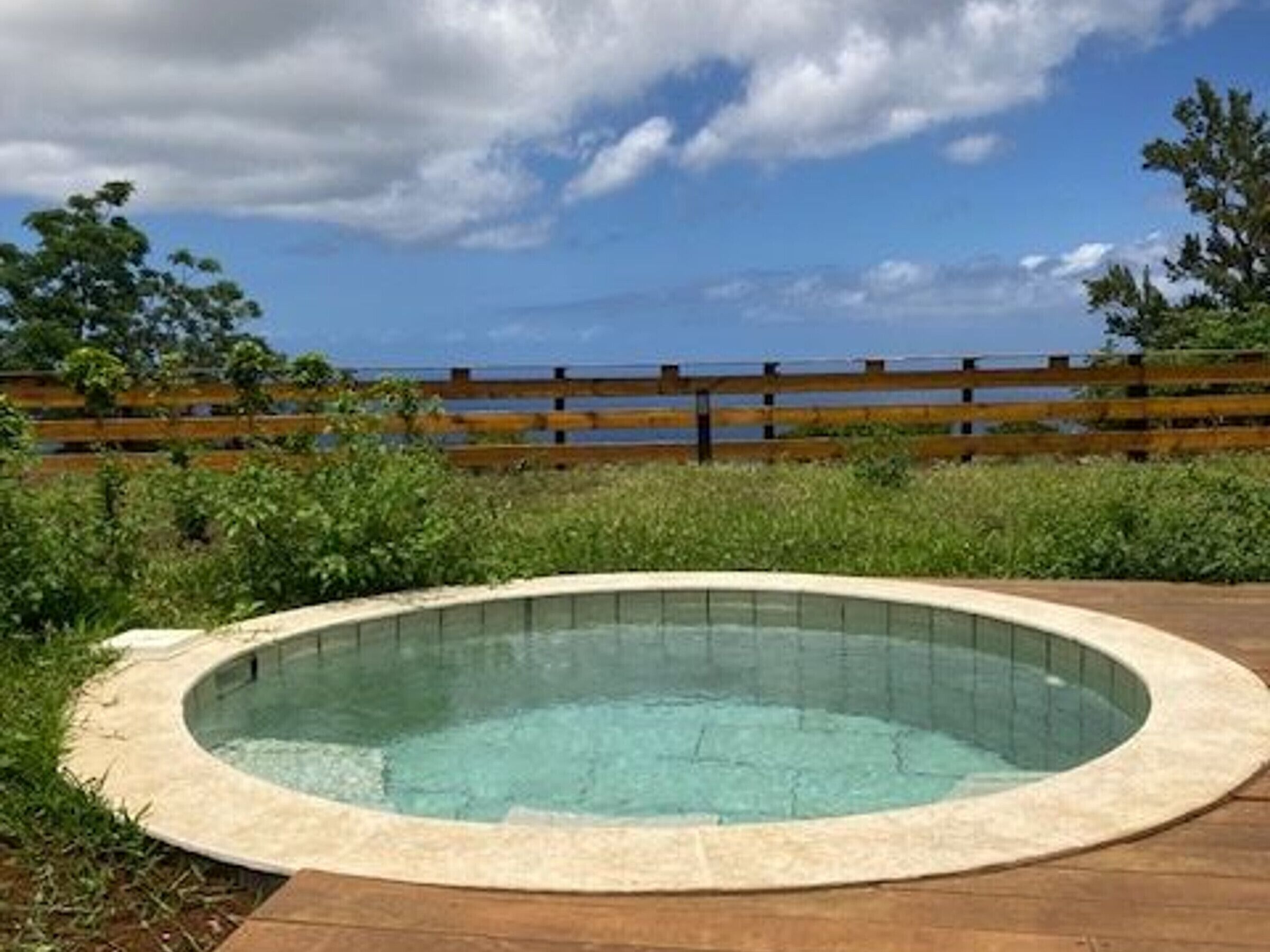 Ein Whirlpool in einem Garten mit einer Holzterrasse und Blick auf das Meer.