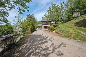 Une route de campagne menant à une maison avec un garage et un patio couvert.