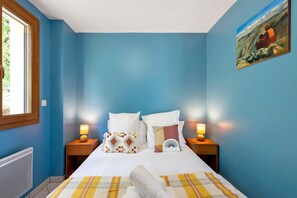 Une chambre à coucher avec un lit, deux tables de chevet avec des lampes, un radiateur et un tableau au mur.