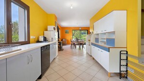 Una cocina con lavavajillas, una mesa de comedor con sillas y una ventana con vistas a la vegetación.
