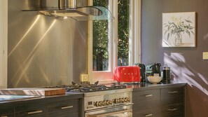 A modern kitchen with a gas stove, a red kettle, and a coffee maker.