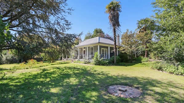 A house with a covered porch, surrounded by lush greenery and a well-maintained lawn.