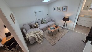 A modern living room with a sofa, coffee table, lamp, and artwork on the wall. - Finchy Cottage - Your charming Beechworth cottage where heritage character meets modern com (Beechworth)