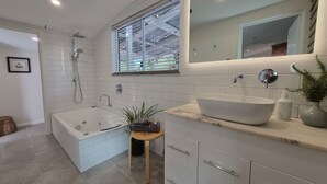 A modern bathroom with a bathtub, a sink, and a window with blinds. - Finchy Cottage - Your charming Beechworth cottage where heritage character meets modern com (Beechworth)