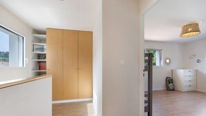Une pièce avec une armoire en bois, une commode blanche, une fenêtre et une bibliothèque.