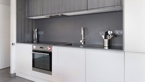 Une cuisine moderne dotée d’un four encastré, d’appareils électroménagers en acier inoxydable et d’un pare-feu gris.