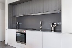 A modern kitchen with a built-in oven, stainless steel appliances, and a grey backsplash. - Maison des Orchidées just 100m from the beach (La Tranche-sur-Mer)