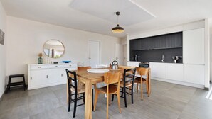 Une cuisine moderne avec des meubles blancs, une table à manger en bois et un plan de travail noir.