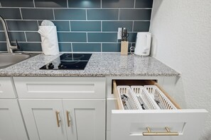 A kitchen with a granite countertop, white cabinets, a built-in stove, and a white towel on the counter. - Modern Centro studio with cozy finishes (Austin)