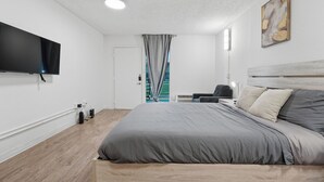 Une chambre d’hôtel moderne dotée d’un grand lit, d’un téléviseur à écran plat, d’un plancher en bois et offrant une vue sur l’extérieur.