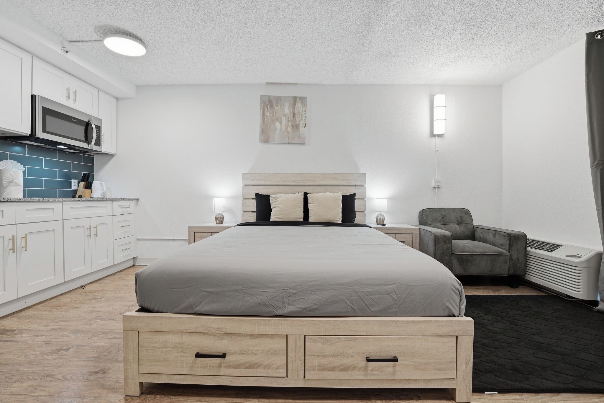 Habitació d'hotel moderna amb llit, làmpades de nit, microones, cadira i calefacció.