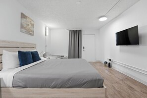 Une chambre d’hôtel moderne équipée d’un grand lit, d’un téléviseur à écran plat, d’un bureau et d’une chaise.