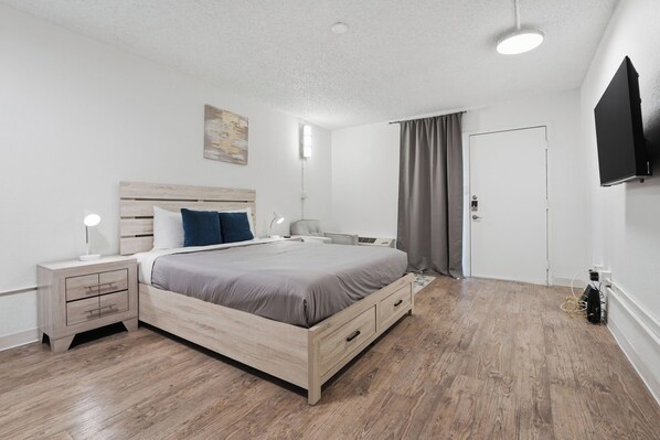 Une chambre à coucher moderne avec un lit en bois, des tables de chevet, un téléviseur à écran plat et un luminaire au plafond.