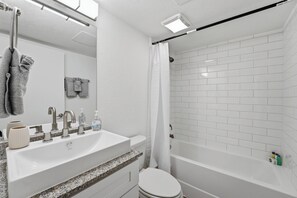Une salle de bain avec un lavabo blanc, un miroir et une douche.